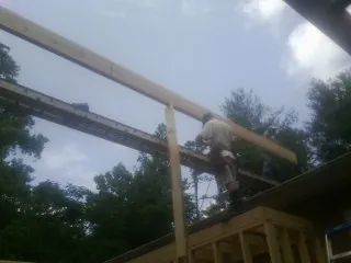 Carpenter setting a ridge beam over a new addition frame — Ice Dam Removal by Roofing Brothers in Mount Solon