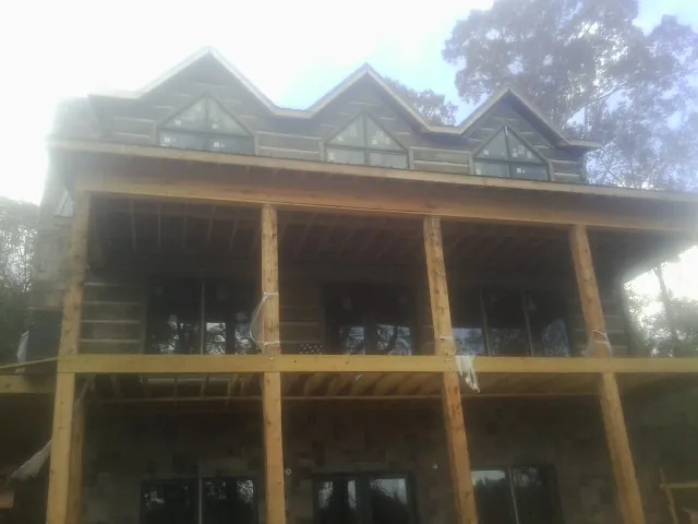 Dormers and porch framing on a large log home under construction — Roof Coating work by our crew in Mount Solon