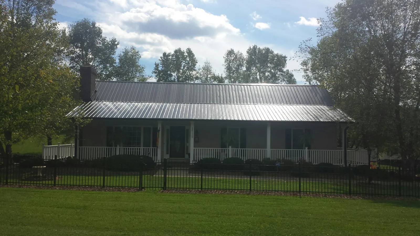 Gray metal roof on a brick ranch with a full width front porch — Gutter Guard Installation work by our crew in Mount Solon