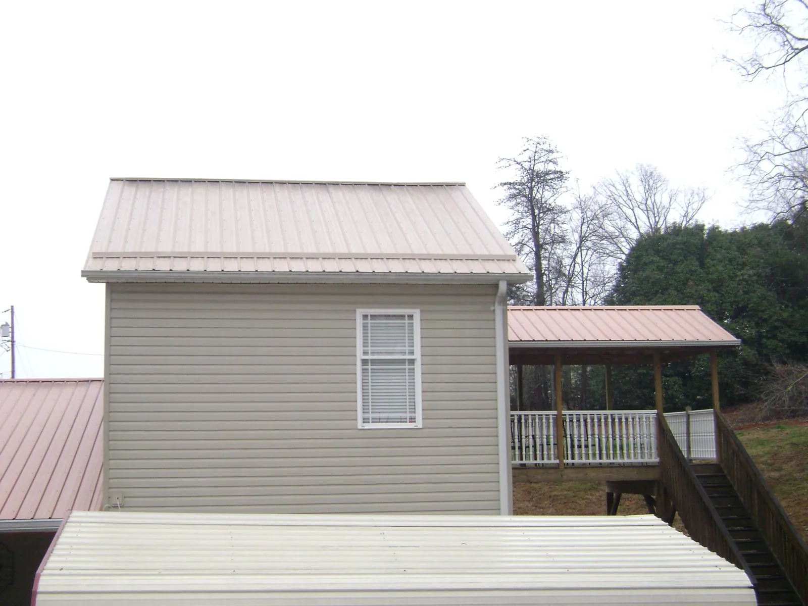 Tan metal roofs on a two story addition and attached porch, from a Roof Replacement job in Mount Solon