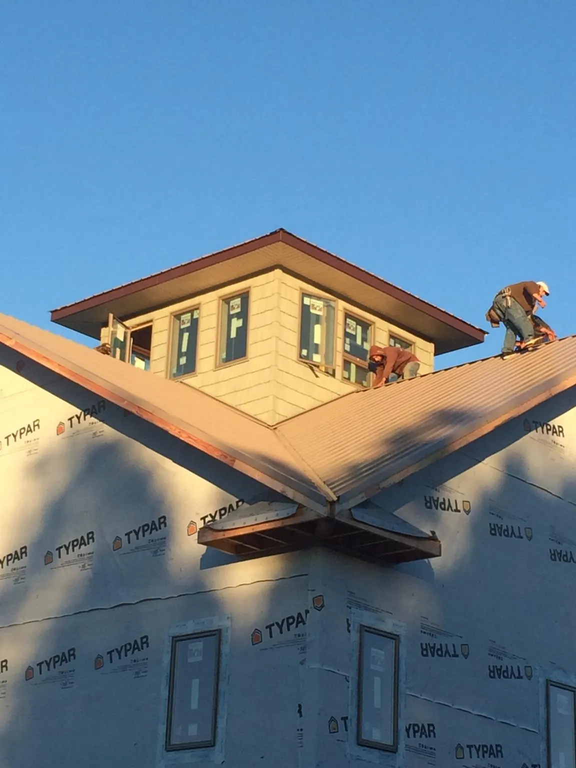 Roofers working around a rooftop cupola on a new metal roof at sunset — Roof Waterproofing in Mount Solon by Roofing Brothers